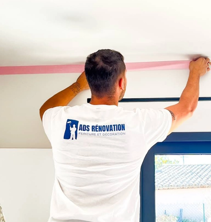 Artisan peintre d'ADS Rénovation en train de peindre un mur intérieur avec résultat final de rénovation