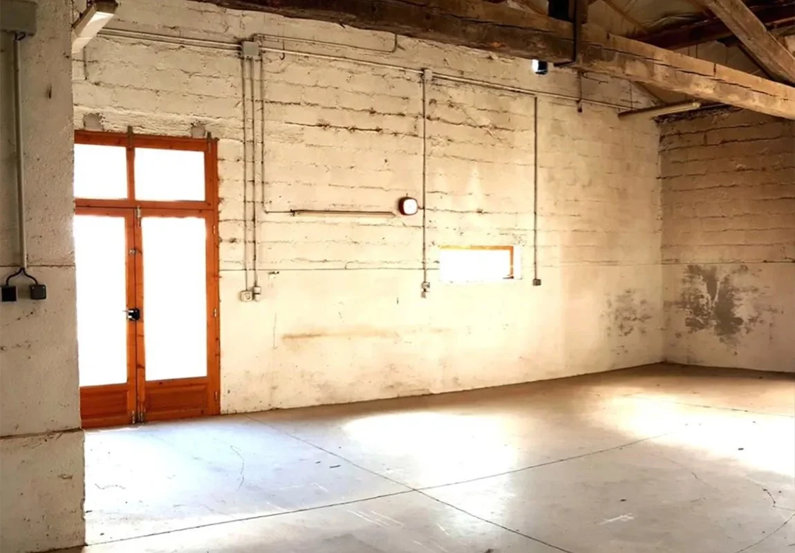 Intérieur d'une maison ancienne avant rénovation par ADS Rénovation dans les Alpes-Maritimes — murs en pierre brute, charpente apparente et menuiseries d'époque à rénover