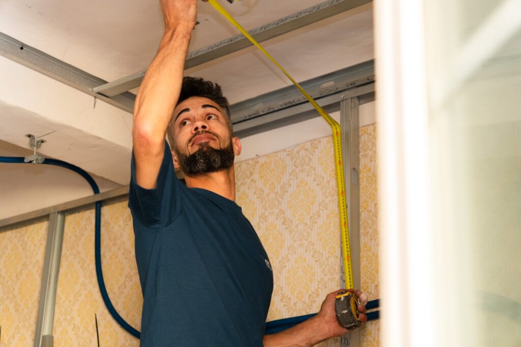 Artisan ADS Rénovation posant l'ossature métallique d'un faux plafond lors d'une rénovation d'appartement